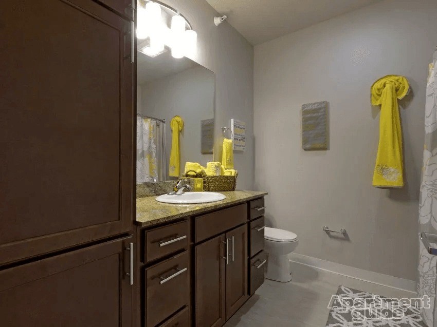 A bathroom with brown cabinets and a white toilet.