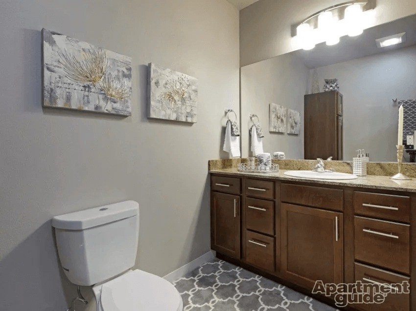 A bathroom with a toilet, sink, and cabinets.
