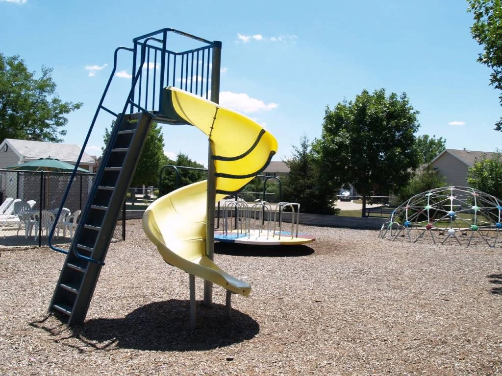 A playground with a yellow slide and a ladder.