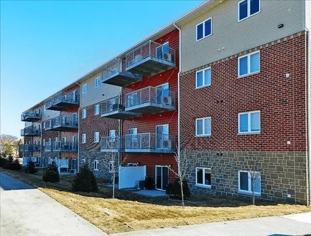A red brick apartment building with balconies on the second floor.
