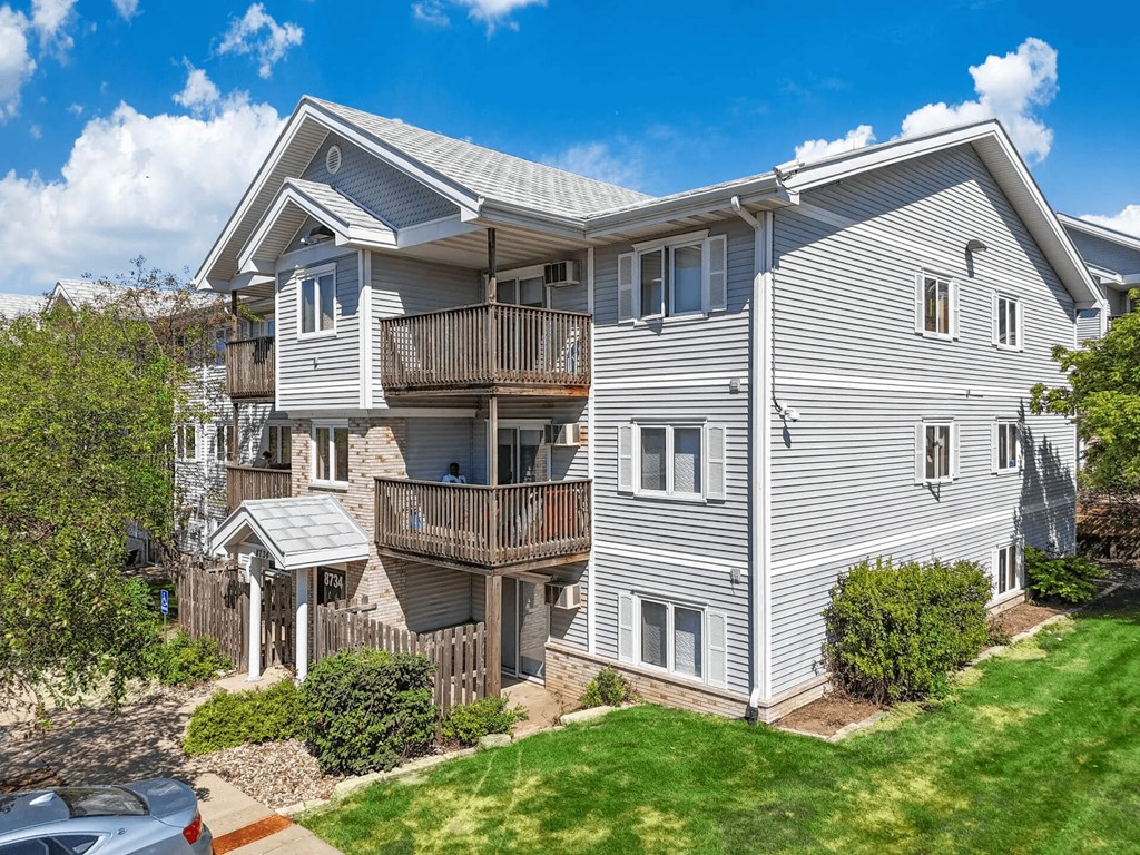 A large two-story house with a balcony and a car parked in front.