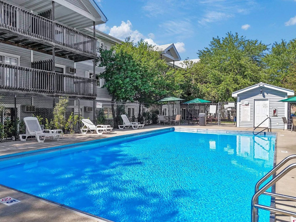 A swimming pool in front of a building with a white chair.