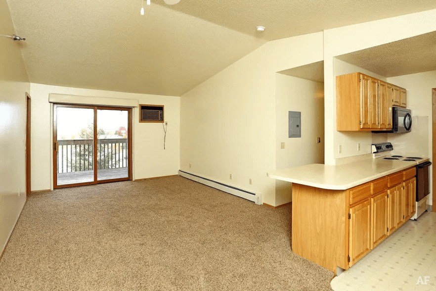 A spacious living room with a kitchen area and sliding glass doors.
