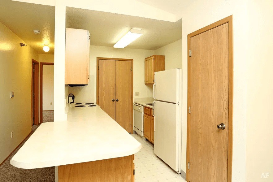 A kitchen with white appliances and wooden cabinets.