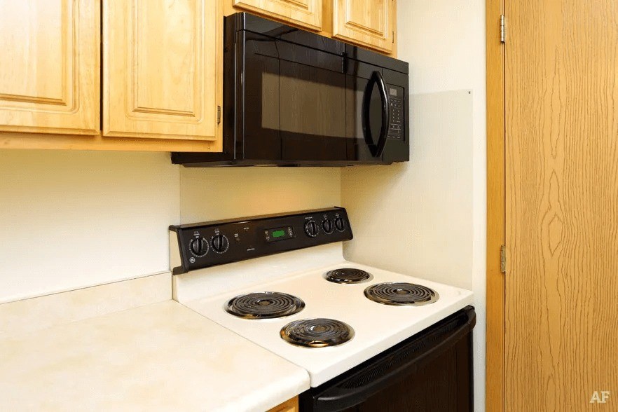 A black microwave oven is mounted above a white stove.