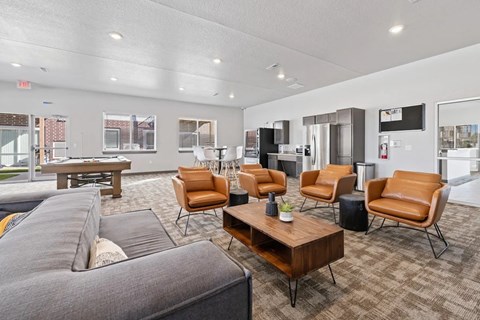 A living room with a grey couch and brown chairs.