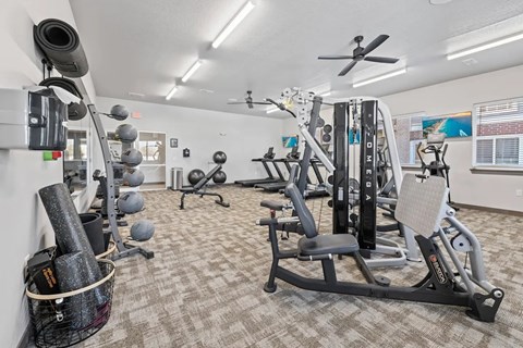 A gym with a variety of equipment including a weight rack, a leg press machine, and a squat rack.