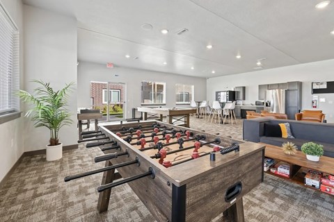 A foosball table is in the middle of a room with a couch and a potted plant.