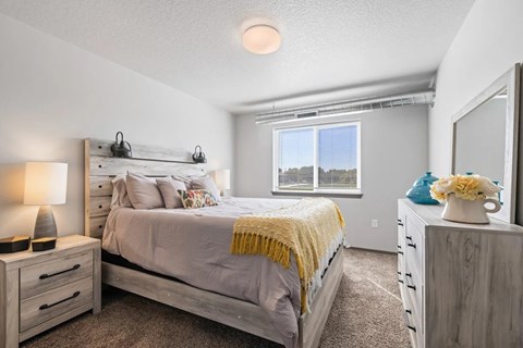A bedroom with a bed, nightstands, and a window.