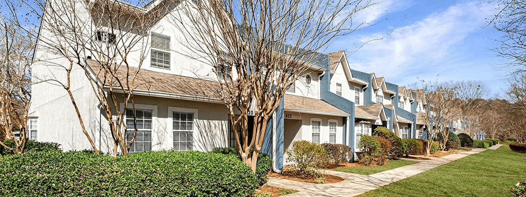 A row of houses with trees in front.