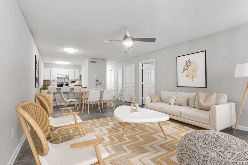 A living room with a white couch, a wooden chair, and a rug.