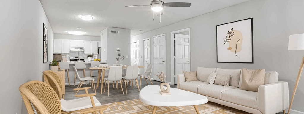 A modern living room with a dining area in the background.