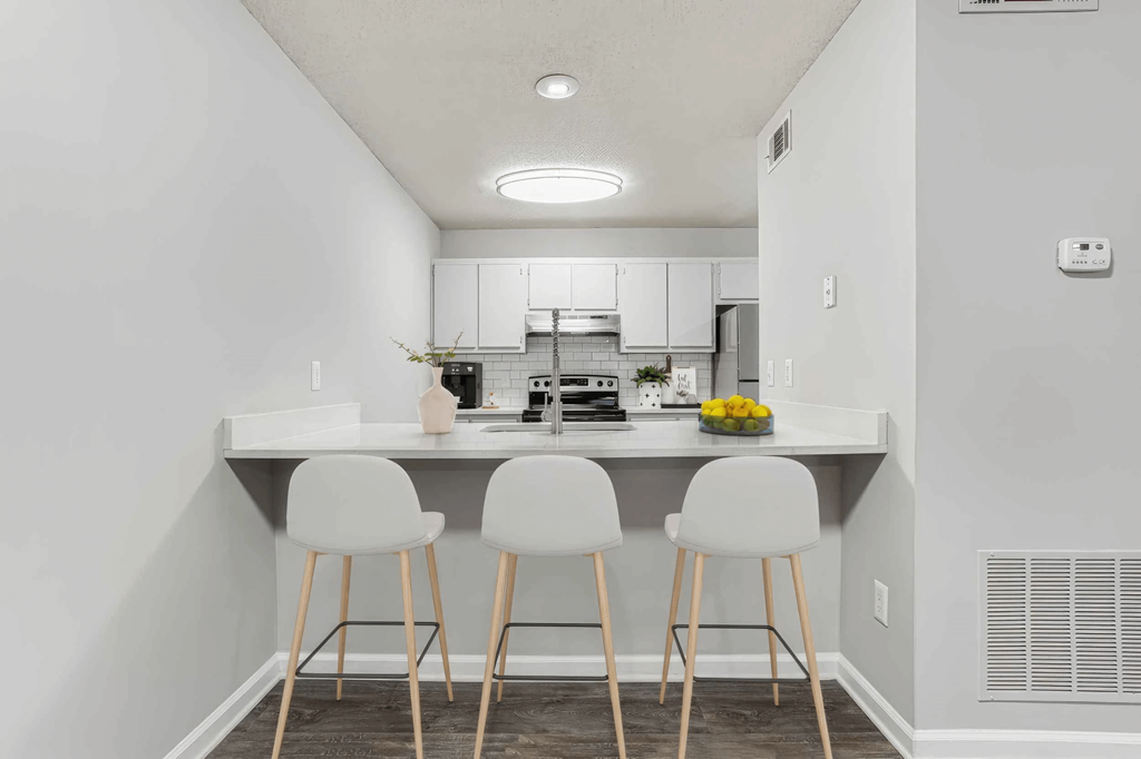 A kitchen with white chairs and a white table.