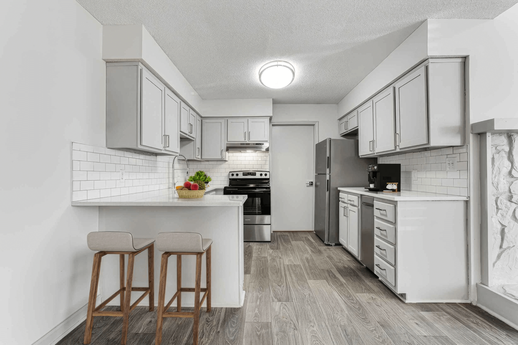 A kitchen with white cabinets and a white tile backsplash.