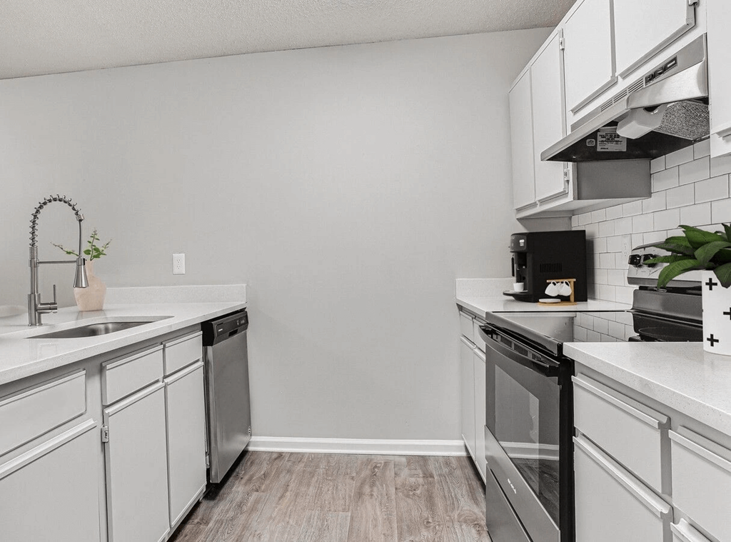 A kitchen with white cabinets and black appliances.