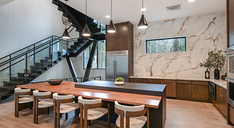 A modern kitchen with a marble backsplash and a wooden dining table with chairs.