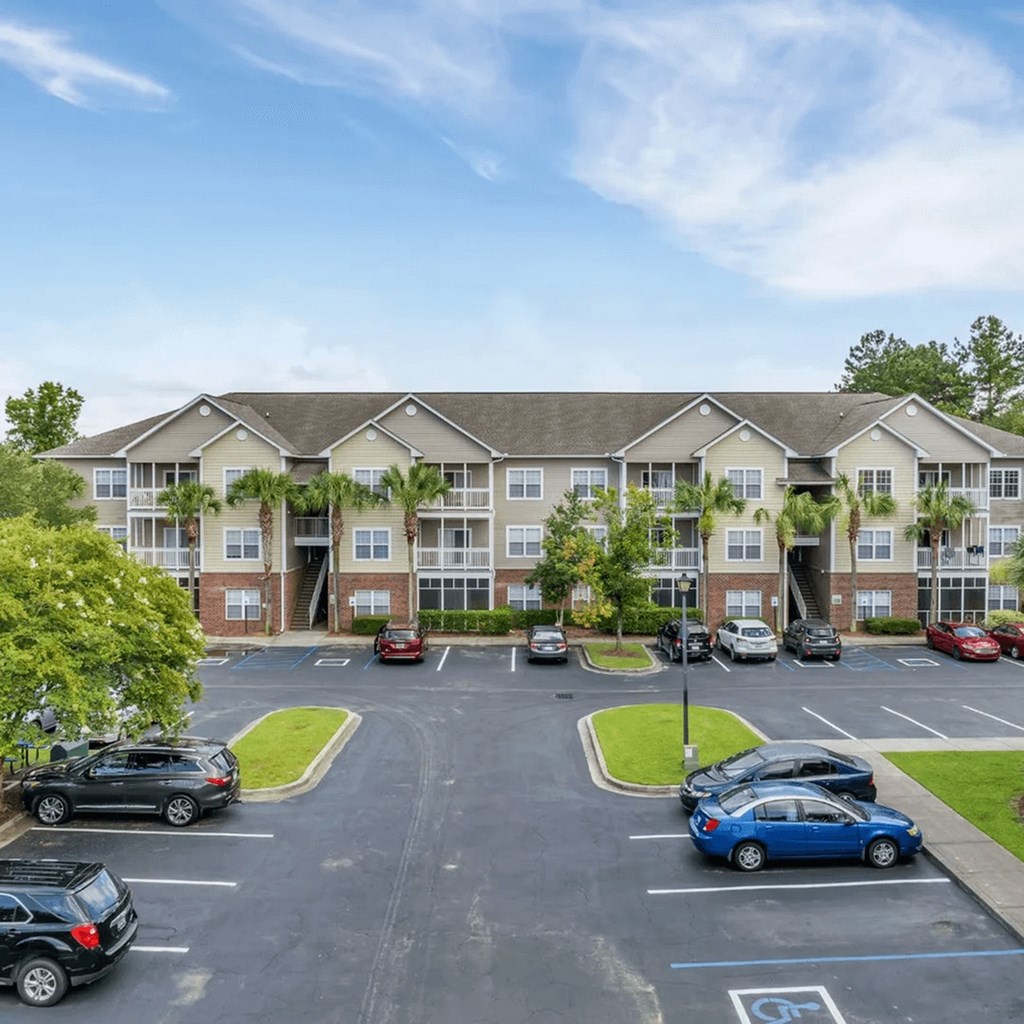 A parking lot in front of a building with cars parked.