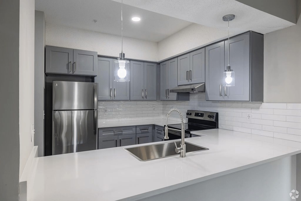 A modern kitchen with a stainless steel refrigerator and a white countertop.