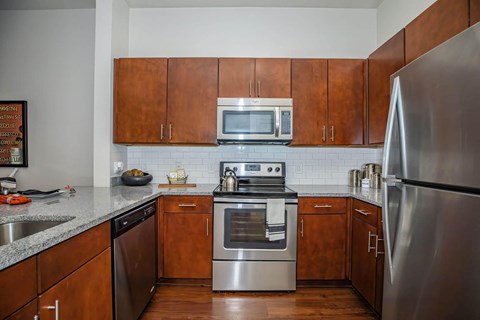 A kitchen with a stainless steel refrigerator, microwave, oven, and dishwasher.at Century Cedar Hill, Cedar Hill, TX
