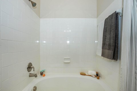 A white tiled bathroom with a white bathtub and a shower head.at Century Cedar Hill, Texas, 75104
