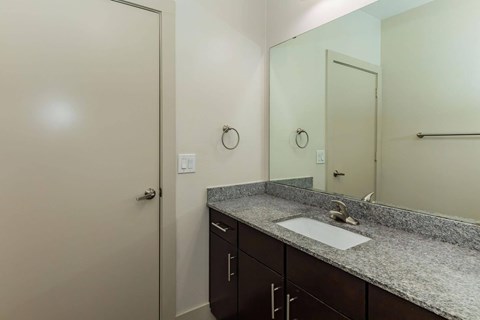 A bathroom with a sink, mirror, and cabinets.at Century Cedar Hill, Cedar Hill, TX