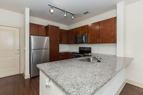 A kitchen with a granite countertop and wooden cabinets.at Century Cedar Hill, Cedar Hill, 75104