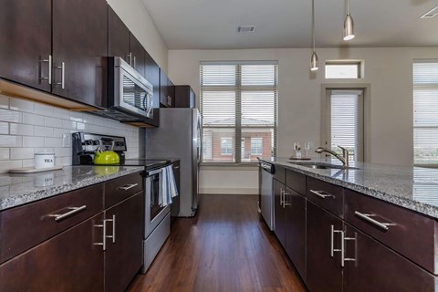 A kitchen with dark wood cabinets and a granite countertop.at Century Cedar Hill, Cedar Hill, 75104