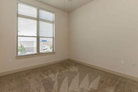 A room with a window and a carpeted floor.at Century Cedar Hill, Texas