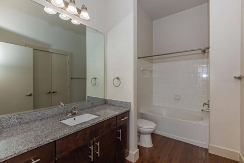 A bathroom with a sink, mirror, toilet and bathtub.at Century Cedar Hill, Cedar Hill Texas