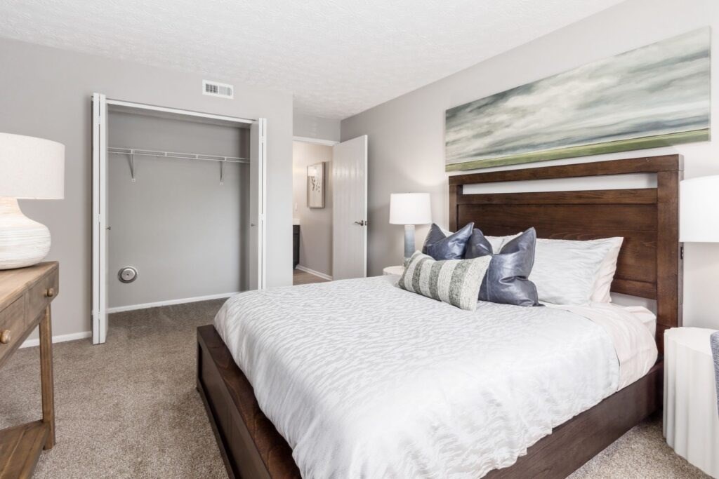 A bedroom with a large bed and a painting on the wall.