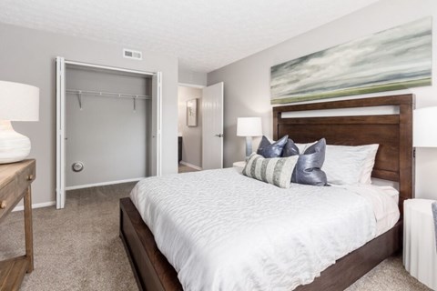 A bedroom with a large bed and a painting on the wall.