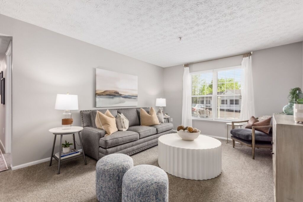 A living room with a grey couch, a white coffee table, and a painting on the wall.