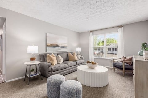 A living room with a grey couch, a white coffee table, and a painting on the wall.