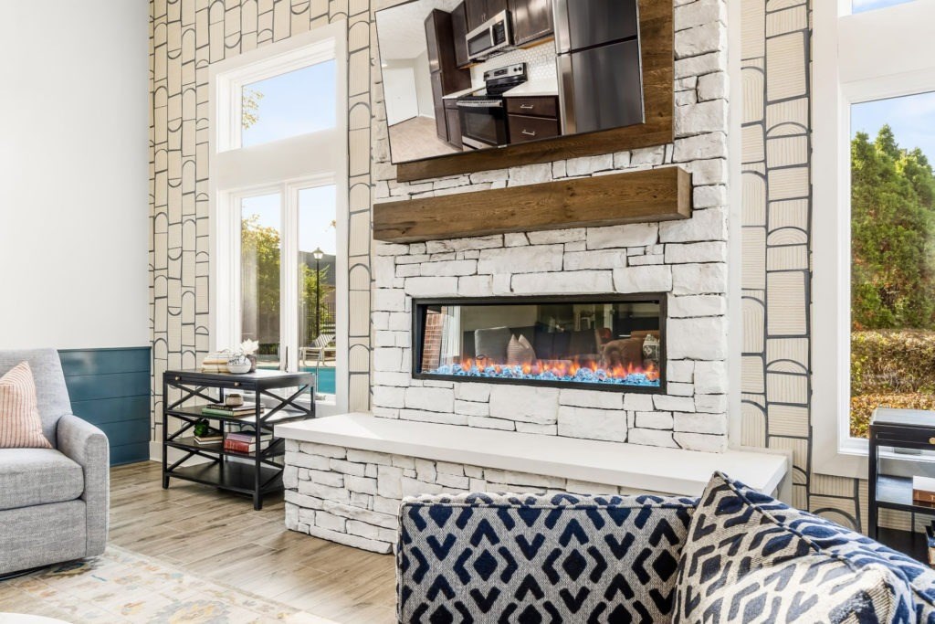 A living room with a fireplace and a grey couch.