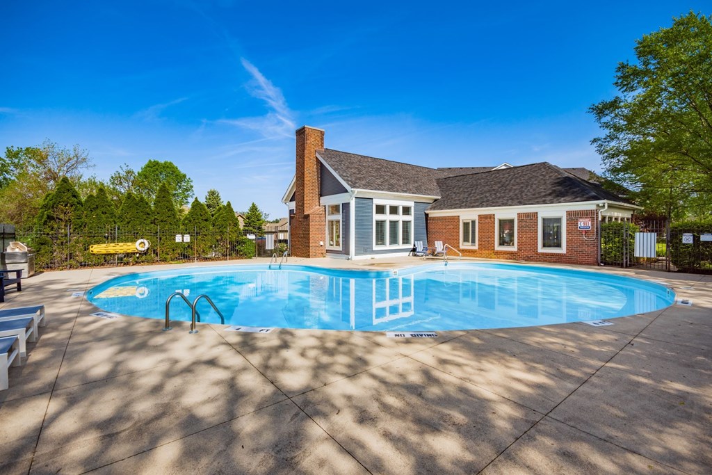 A pool in front of a house with a blue sky.