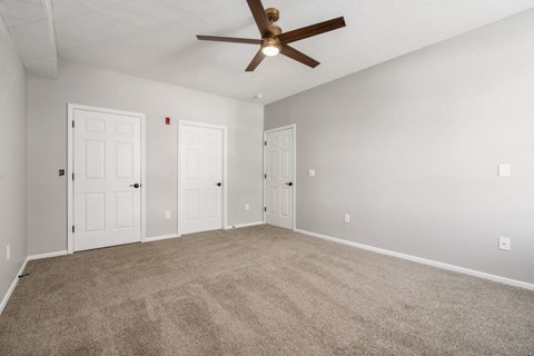A room with a ceiling fan and carpeted floor.