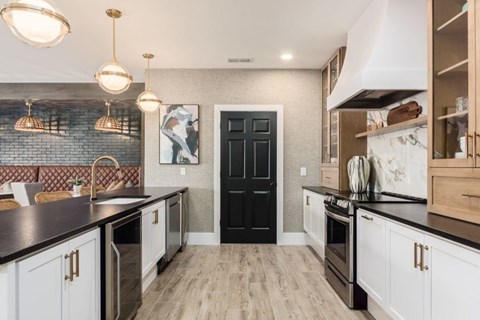 A kitchen with black and white cabinets and a black door.