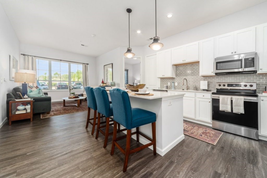 A kitchen with white cabinets and a large island with blue chairs.