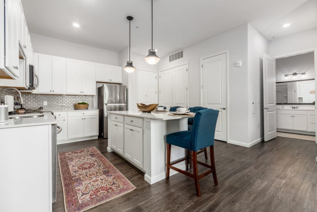 A kitchen with white cabinets and a blue chair.