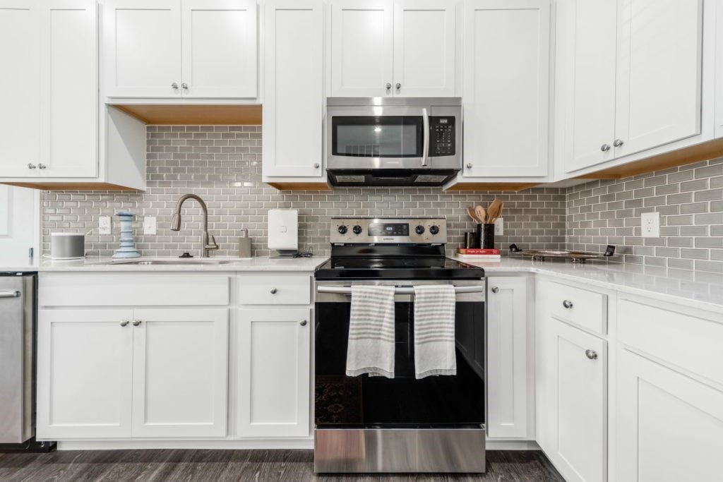 A kitchen with white cabinets and a black stove top.