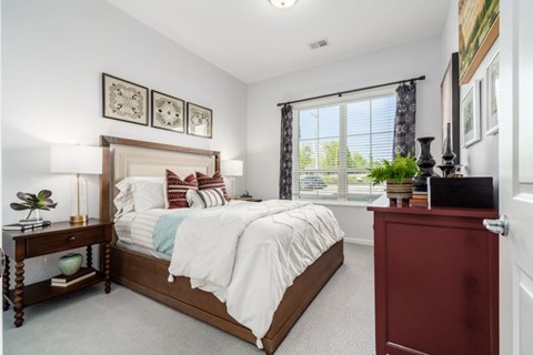 A bedroom with a large bed and a red dresser.