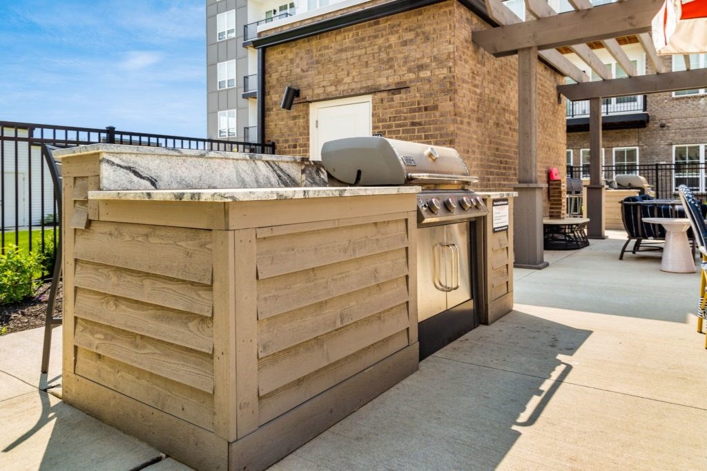 A wooden outdoor kitchen with a grill and sink.