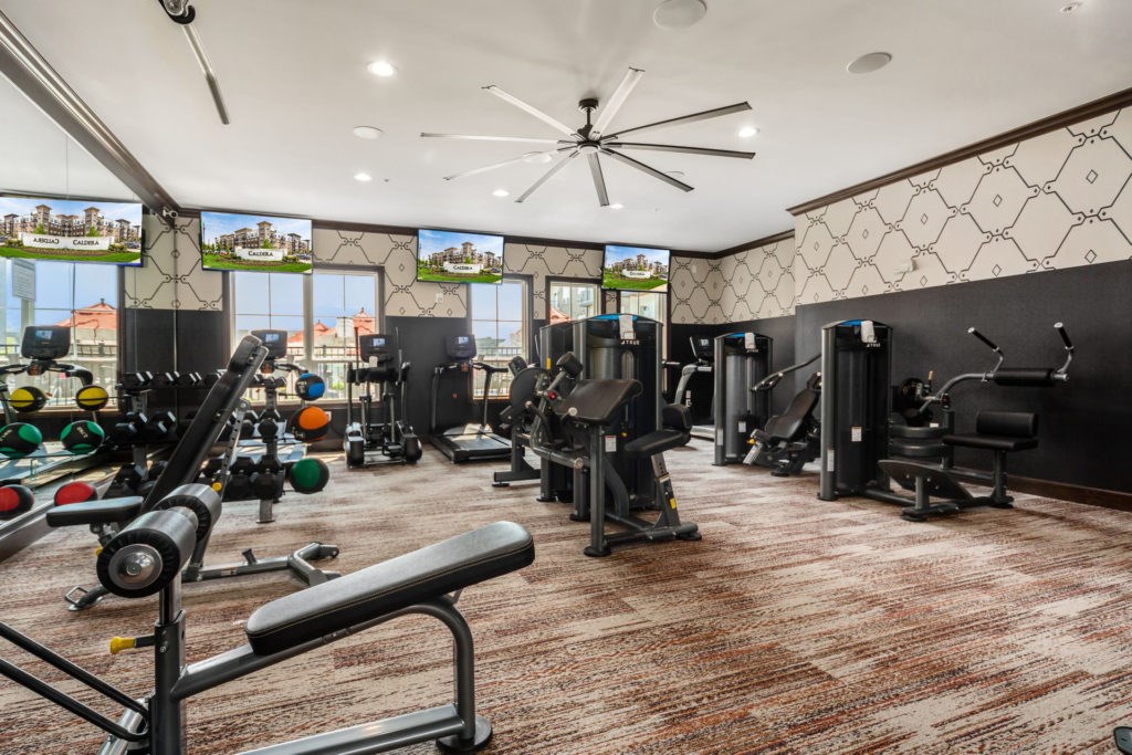A gym with a variety of equipment including treadmills, weights, and exercise machines.