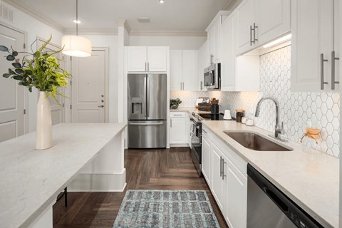 A kitchen with white cabinets and a marble countertop.