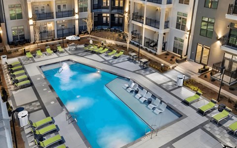 A large swimming pool surrounded by lounge chairs in a courtyard.