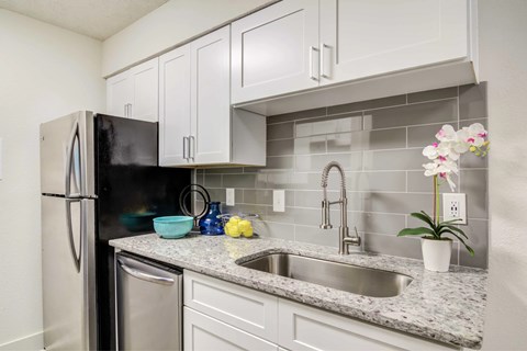 A kitchen with a black fridge and white cabinets.