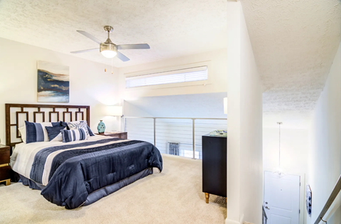 A bedroom with a large bed and a ceiling fan.