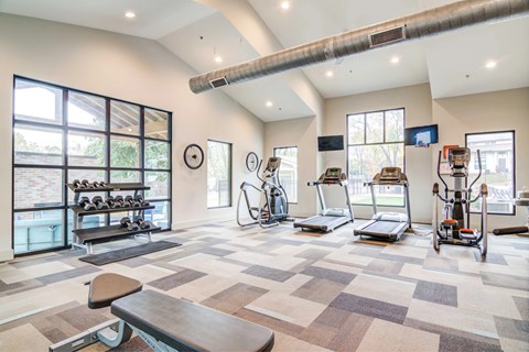 A gym with a variety of equipment including treadmills, exercise bikes, and weight machines.