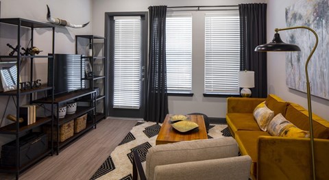 A living room with a yellow couch and a black bookshelf.