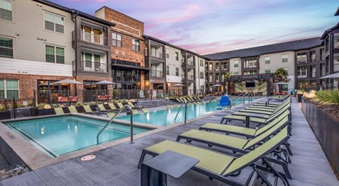 A swimming pool surrounded by sun loungers and a building in the background in Fort Worth. TX.